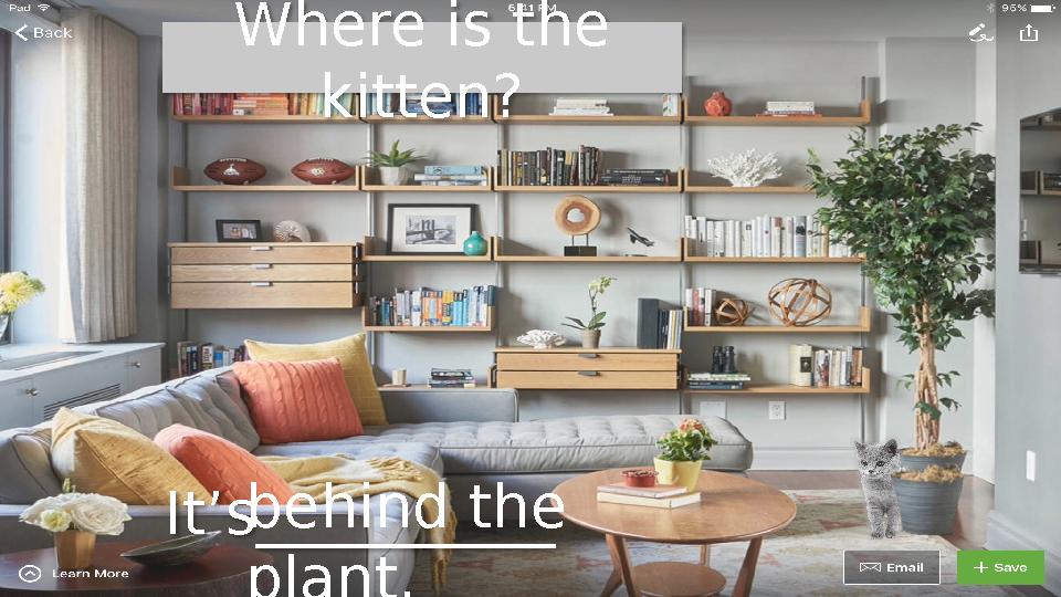 Where is the kitten? It’s__________ behind the plant.